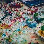 assorted-color bottles on white surface with paint scribbles