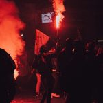 people standing on the street with red smoke