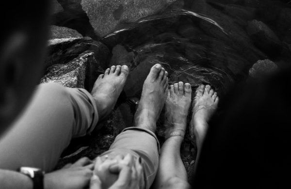 grayscale photo of persons feet on water